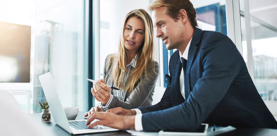 Zwei Mitarbeitende arbeiten gemeinsam am Laptop und besprechen Dokumente.