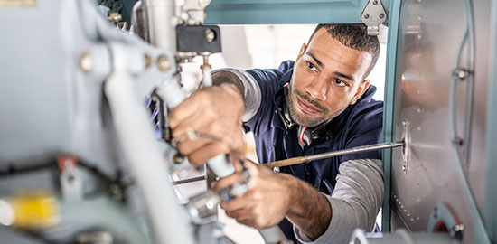 Ein Mitarbeiter f&uuml;hrt Wartungsarbeiten an einer industriellen Maschine durch.