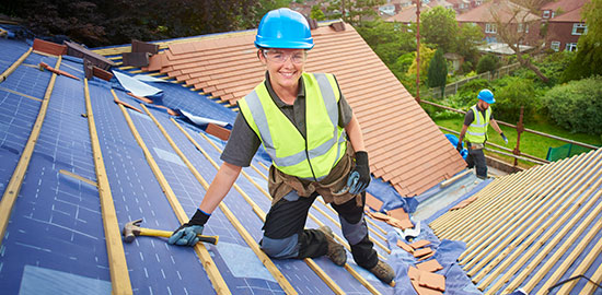 Ein Dachdecker arbeitet auf einem Hausdach und befestigt Dachmaterial.