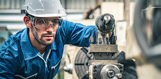 Ein Facharbeiter steuert eine Maschine zur pr&auml;zisen Bearbeitung von Metallteilen.