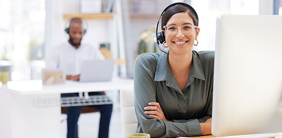 Eine Mitarbeiterin mit Headset sitzt am Computer und betreut Kunden.