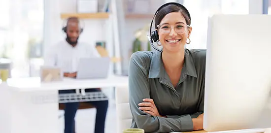 Eine Mitarbeiterin mit Headset sitzt am Computer und betreut Kunden.